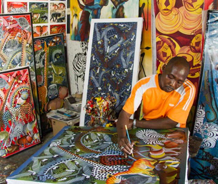 A local craftsman paints his canvases at a market in Stone Town.
