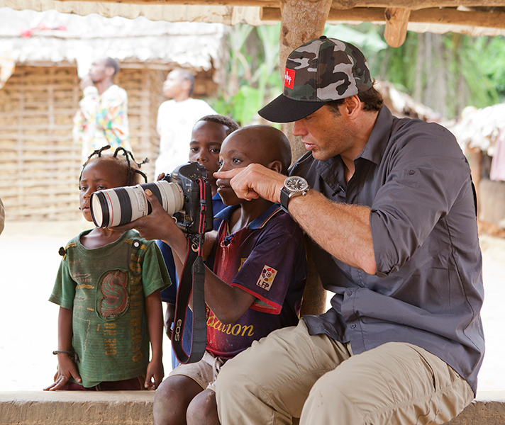 Terrence teaches a young boy how to use his camera.