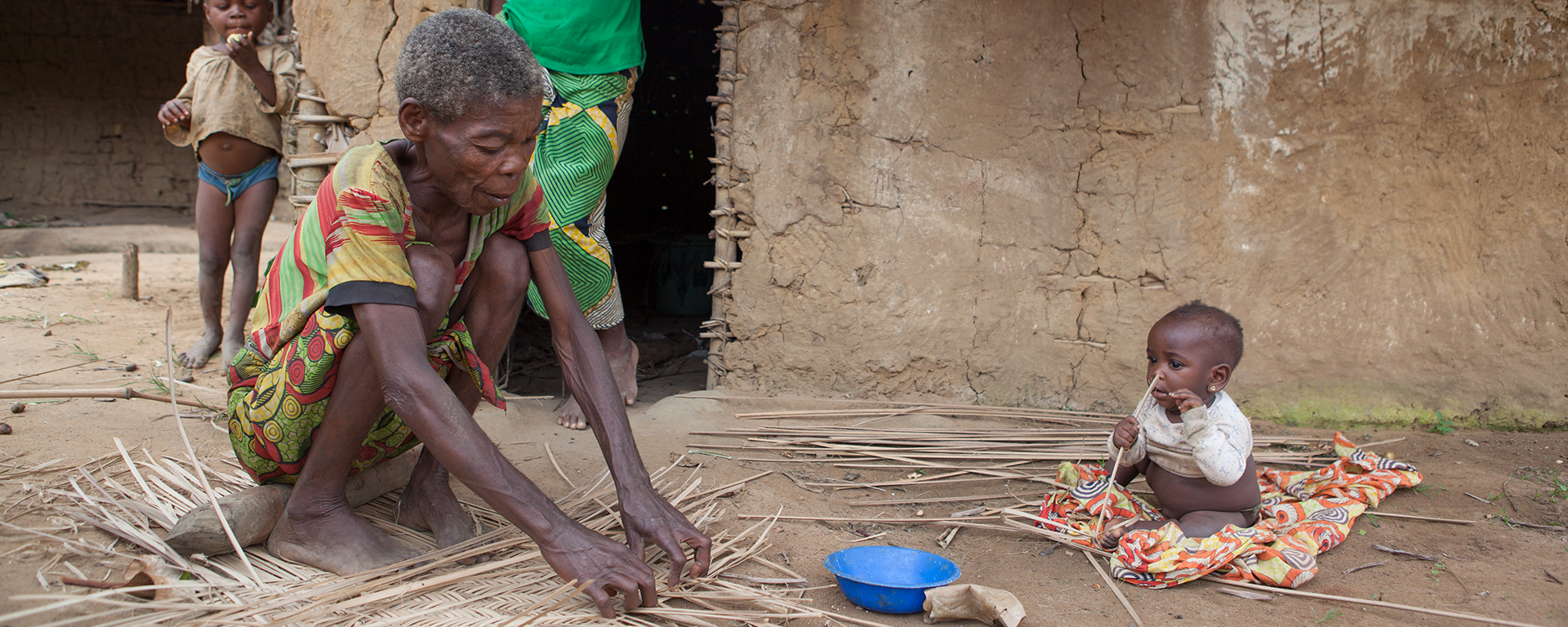 A craftswoman weaves a basket out of dried leaves.