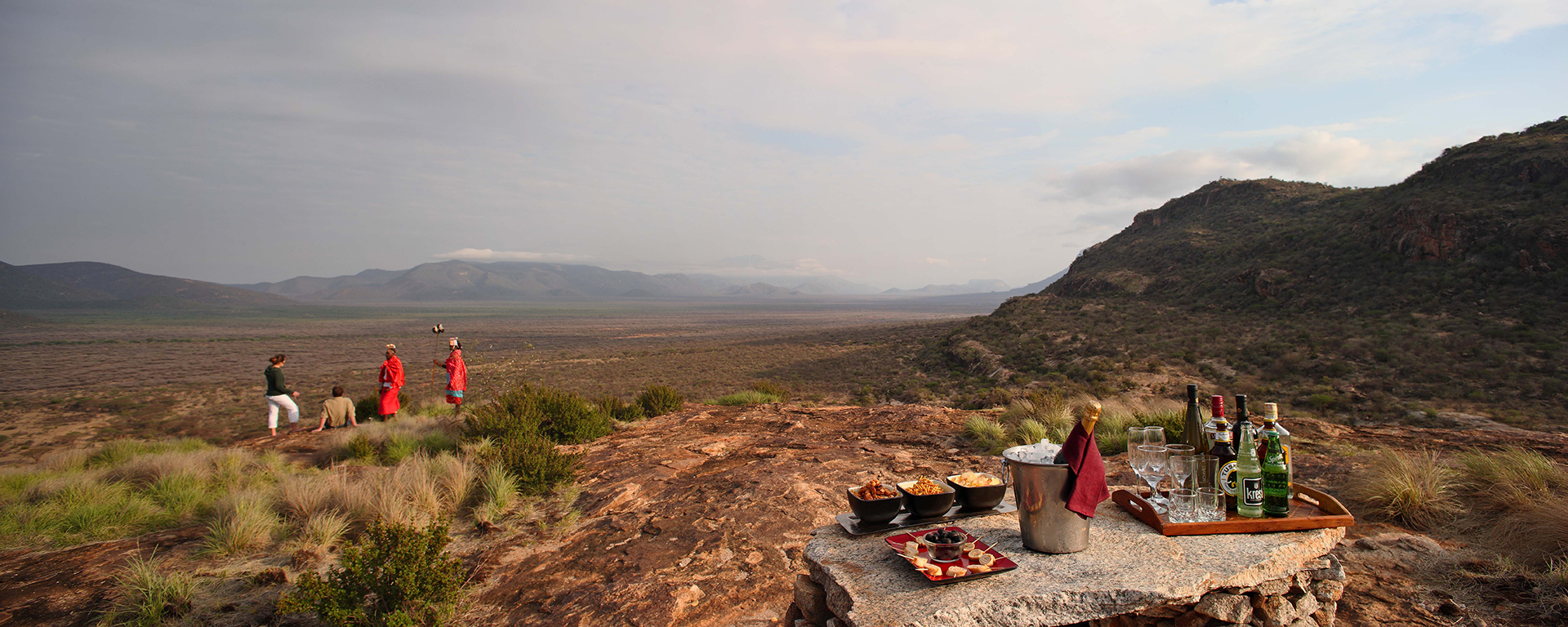 Sundowners at a scenic outlook - under the watchful eye of Maasai guides - are a tradition on Kenyan safaris.