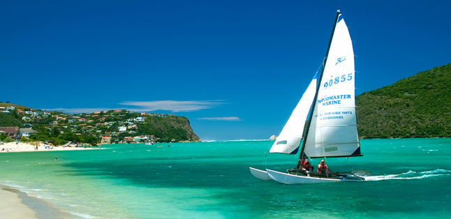 A yacht sails across the turquoise Knysna lagoon, one of the popular towns situated on the Garden Route.