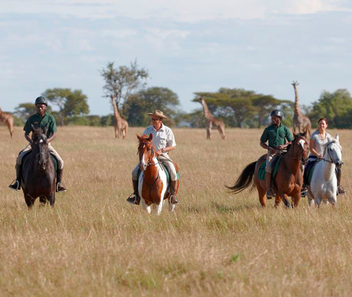 A group of riders with their guides enjoy a horse-back safari in Tanzania's wildlife-rich Grumeti region.