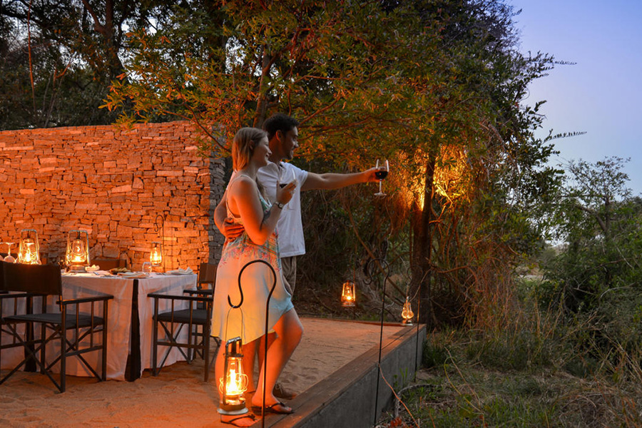 Couple enjoy the view ‌before sitting down for dinner at a safari camp in Africa.