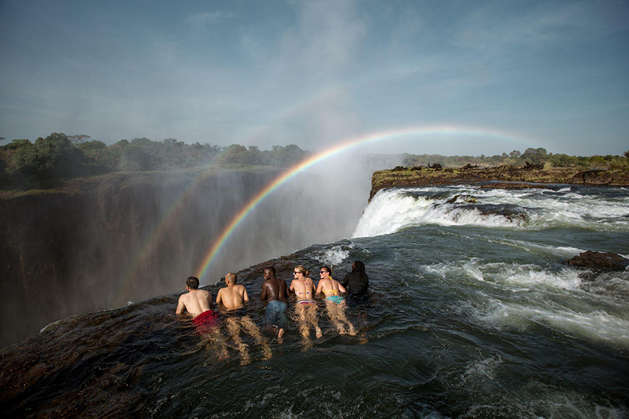 People swimming at the edge of Devil's Pool in Victoria Falls, Zambia.